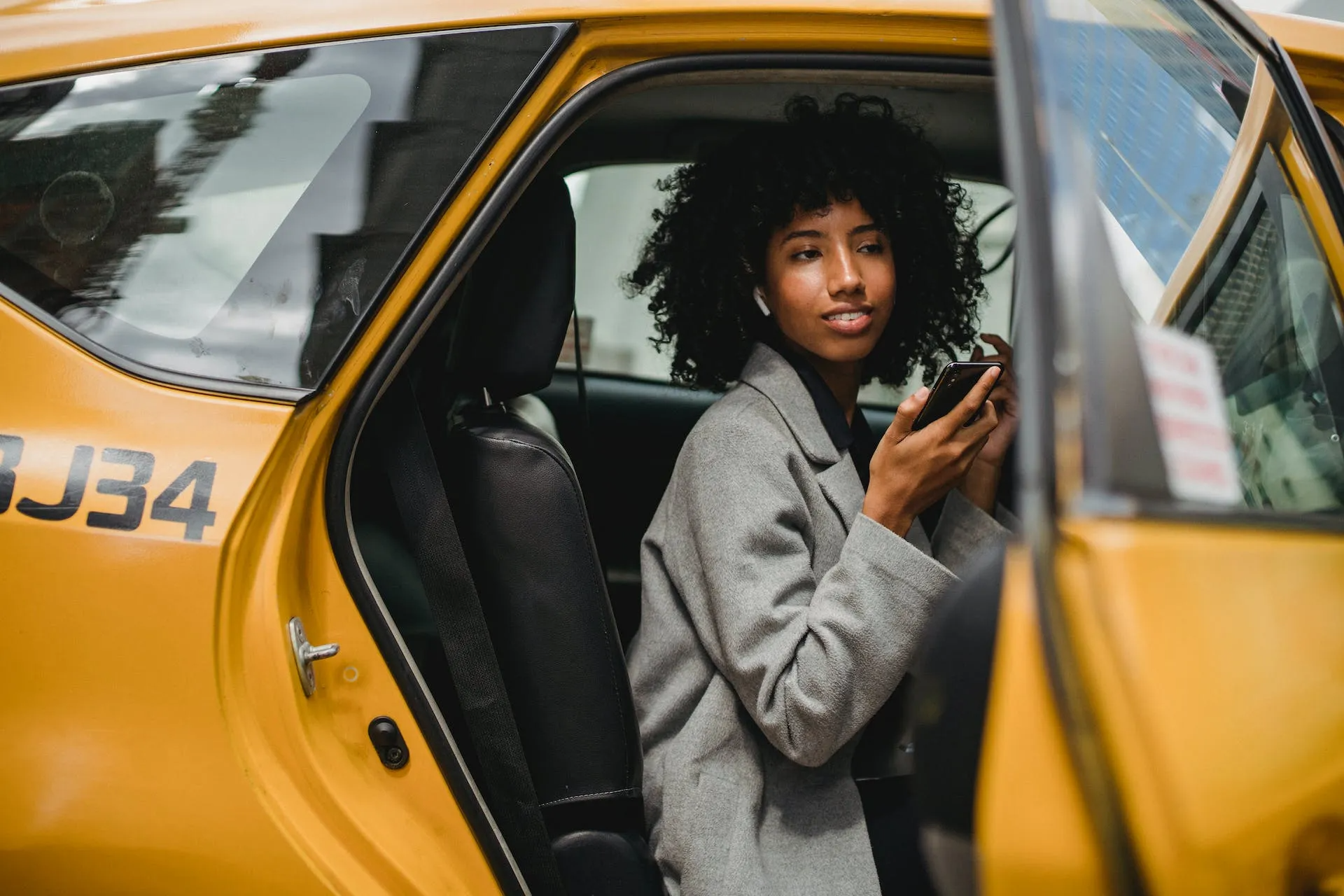 Girl sitting in yellow car using phone